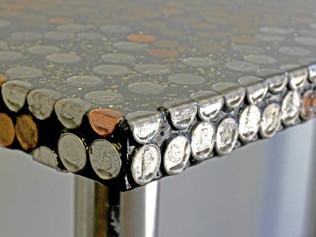 A tabletop covered with coins and layers of resin
