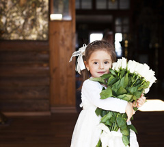 A little girl in her baptism dress with an armfull of flowers